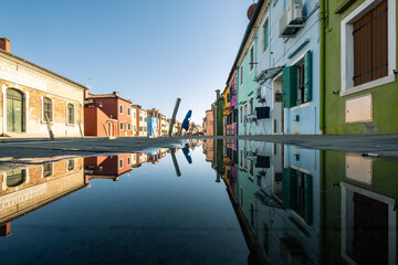 Reflection of the typical houses in a puddle on the Burano island, Veneto, Italy