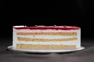 Half or slice of white chocolate mousse and strawberries cake isolated on black background. Copy space. High quality photo. 