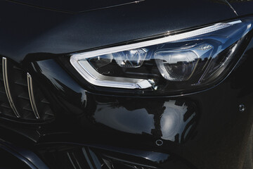 Plakat Black luxury sports car closeup. Modern LED headlights with lenses. Aggressive design. Car showroom. Closeup. 