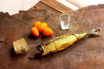 Smoked mackerel tied with cooking twine, on a rustic rusty background. Appetizing smoked fish on kitchen board. Mediterranean food