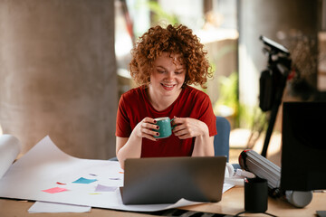 Beautiful businesswoman working on project. Young woman with curly hair drinking coffee..