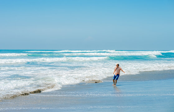 single Chinese young man running and jumping on Parangtritis beach, Yogyakarta, Indonesia.