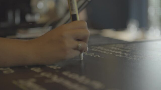 close-up of a hand writing the menu of a restaurant