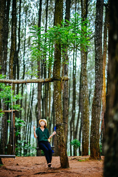 Single Asian girl having fun in forest park at Hutan Pinus Pengger, Yogyakarta, Indonesia.