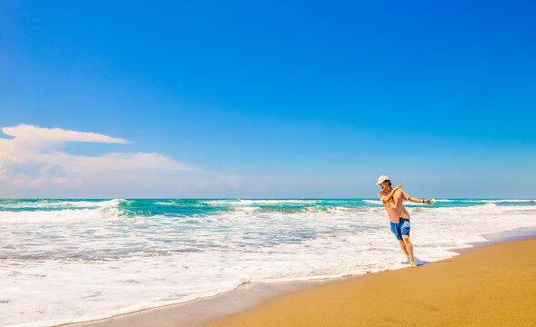 single Chinese young man running and jumping on Parangtritis beach, Yogyakarta, Indonesia.