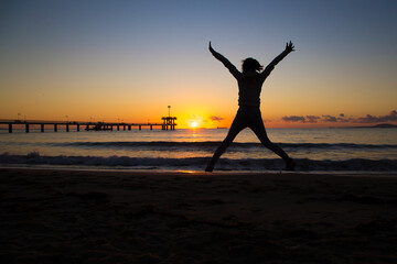 Fototapeta premium silhouette of a jumping person on the beach at sunset