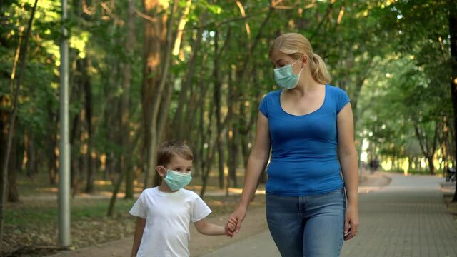 Mother and child in medical masks walk in the Park