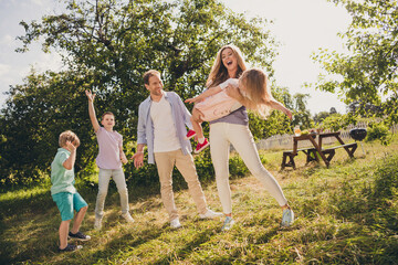 Full body size photo of big full family five people three little kids gathering relax mom hold daughter funny game sons dance on sunny summer day comfort fenced home park backyard outside