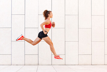 Concept of sporting success. strong girl runs and jumps high against the background of the city wall.