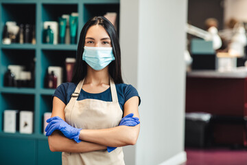Beauty master in protective mask and gloves standing at hairdresser's interior, empty space