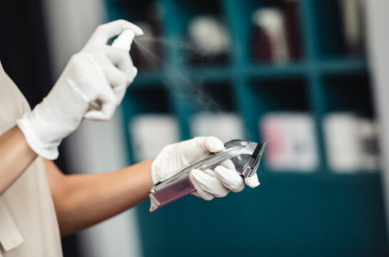 Close up of hairdresser disinfecting electric trimmer after work - Powered by Adobe