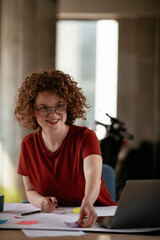 Beautiful businesswoman working on project. Young woman with curly hair in office..