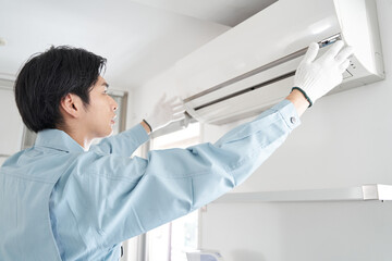家庭用エアコンの取り付けをする日本人男性電気工事士