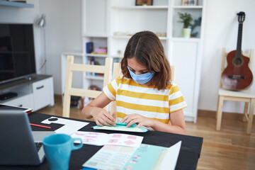 Naklejka premium Girl child learning at home during virus pandemic and school restrictions.