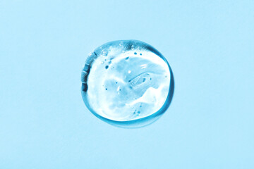 Transparent hyaluronic acid gel drops on a blue background.