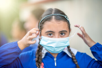 Fototapeta na wymiar Young girl wearing face mask returning to school after pandemic