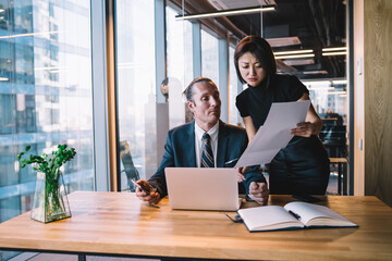 Serious colleagues doing paperwork together in modern office