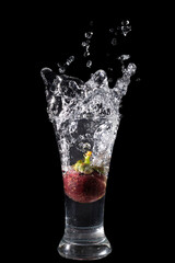 Mangosteen Dropped Into a Glass with a Big Splash , isolated on black
