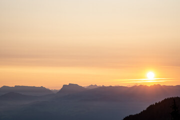 Sonnenaufgang über dem Berner Oberland. Alpen mit Dunst und orange gefärbtem Himmel in Morgenstunde Herbst Stimmung