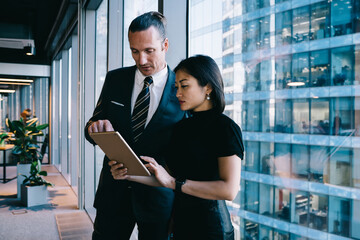 Concentrated coworking man and woman using tablet together in workplace
