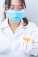 Close up Scientist holding Omega 3 capsule in labcoat