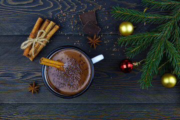 Homemade hot chocolate with cinnamon in a white enamel mug on a dark wooden background. Winter Christmas drink made from cocoa.