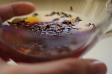 transparent cup with black tea in female fingers.