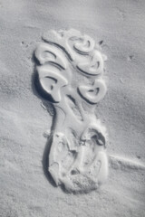 Shoe footprint on white snow. There is a clear footprint on the white blanket of snow.