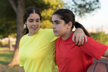 Obraz premium Two young girls chatting excitedly on their way to the basketball court.