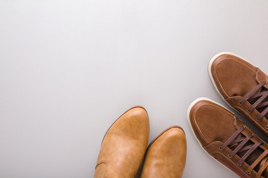 Male and female brown leather boots on gray floor background. Closeup. Footwear for daily walking in autumn season. Empty place for text. Top down view.