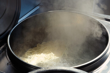 Boiling fresh raw chinese noodles in a large steel pot