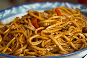 A bowl of fried Chinese noodles with chicken and vegetables