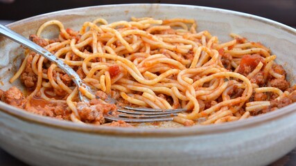 Pasta with meat and tomato sauce. Spaghetti bolognese with fork in the bowl. Closeup view