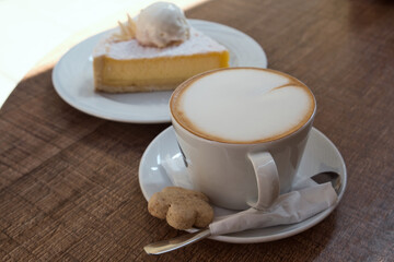 Delicious Serbian breakfast - a cup of hot cappuccino with milk foam and sweet lemon pie with vanilla ice-cream