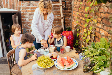 Blond curly mother with two children on terrace or backyard at summer time. Parenting difficulties child with disabilities concept. Childern need care, presence and love.