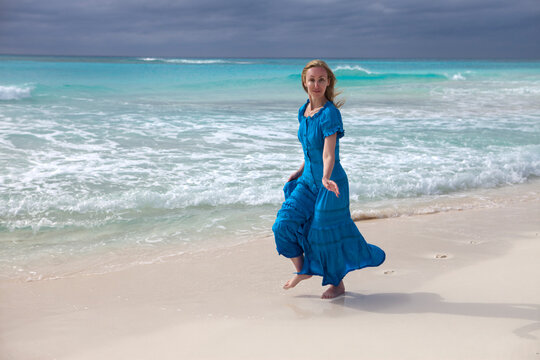 The woman in a long blue dress goes on the sea coast Cayo Largo island, Cuba