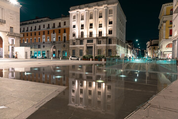 Fototapeta na wymiar Urban movement in a night square. Victory Square, Brescia, Italy..