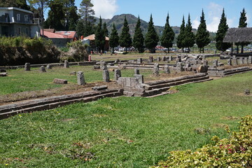 Beautiful scenery at Arjuna temple consisting of trees, boulders, mountains, and white clouds against a backdrop of blue sky in Wonosobo, Indonesia.