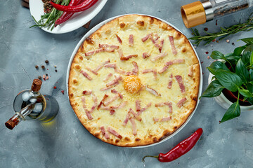 Italian pizza with carbonara sauce, bacon, parmesan and yolk on a gray background. Top view, food flat lay