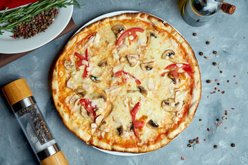 Italian pizza with bacon, mushrooms, tomatoes, melted cheese on a gray background. Top view, food flat lay