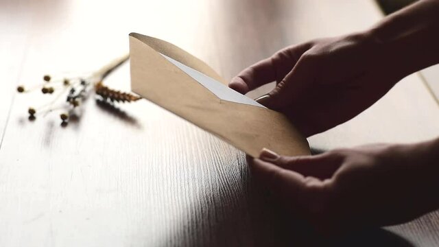 person hands open up kraft envelope with letter  on brown background