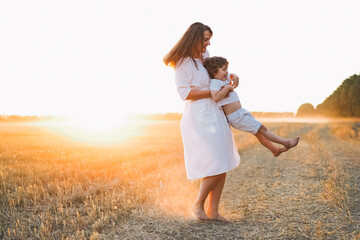 Woman playing with her child on the field during sunset.