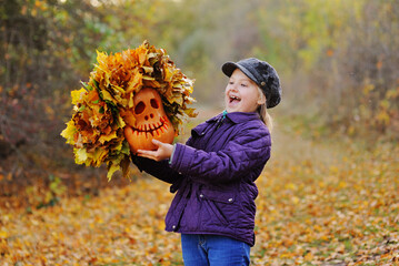 child-a little girl in a cap and purple jacket screams feigning fright and holds a pumpkin Jack's...