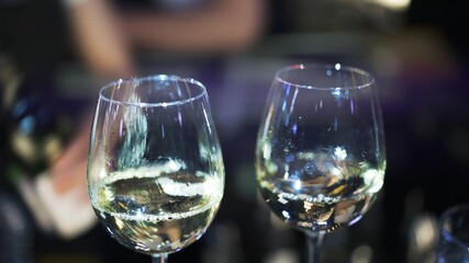 Two glasses of white wine on blurred background in bar. Close up shot of two drinks in bar, blurry lens flare shot of alcohol drinks in the restaurant