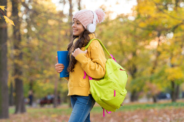 concept of online education. child carry books for study. girl in earphones with school bag. kid listen music in autumn park. fall is a time for study. back to school. Peaceful morning