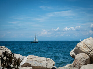 View on sailing yacht over the rocks. Blue sky with clouds on background. Active lifestyle.