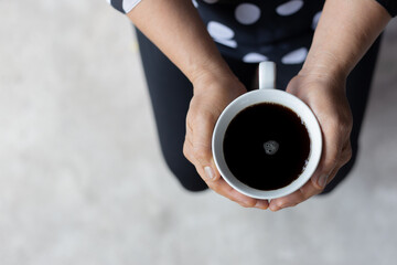 Fototapeta na wymiar Coffee cup on the hand of elderly women