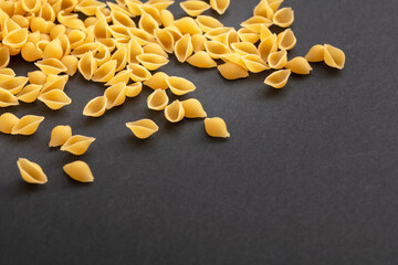 Pasta shells on black background, closeup view. Cooking italian cuisine concept