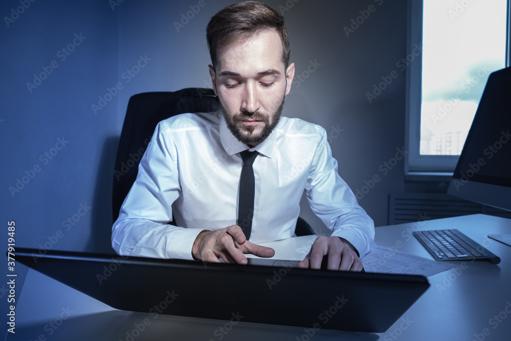 Poster the businessman works on a laptop. work from home. a young businessman works with a laptop in the of