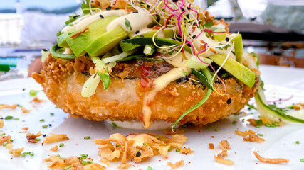 Sushi-food hybrids trend. New Design Delicious White Rice Hamburger ingredients salmon, avocado, mayonnaise, fresh vegetables, fried onion.